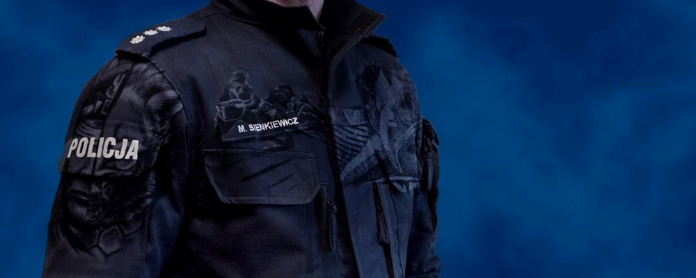 Grafika na której ukazano granatowy mundur poicyjny z napisem Policja i nałożonymi na niego komputerowo tatuażami. Grafika ma na celu przykuć uwagę osób posiadających tatuaże i zachęcić do przeczyatnia informacji na temat czy Policjant może posiadać tatuaże.